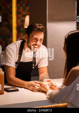Barista, Der Kaffee Flirtet Und Den Weiblichen Kunden Im Café Aufsteht Stockfoto