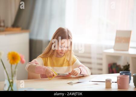 Portrait von süßen Mädchen, die Ferienkarte für Mütter Tag oder Valentinstag machen, während sie am Tisch in gemütlichem Heim sitzen, Kopierer Stockfoto