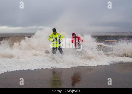 New Brighton, Wirral, Großbritannien. Februar 2020. Fotografen nutzen die Gelegenheit, die von Storm Ciara verursachten Wellen zu erfassen, während sie in die Promenade von New Brighton auf der Wirral stürzen. Ein Fotograf wird von den Wellen, die über die Promenadenwand krachen, von den Füßen gefegt. Kredit: Christopher Middleton/Alamy Live News Stockfoto