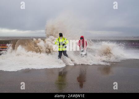 New Brighton, Wirral, Großbritannien. Februar 2020. Fotografen nutzen die Gelegenheit, die von Storm Ciara verursachten Wellen zu erfassen, während sie in die Promenade von New Brighton auf der Wirral stürzen. Ein Fotograf wird von den Wellen, die über die Promenadenwand krachen, von den Füßen gefegt. Kredit: Christopher Middleton/Alamy Live News Stockfoto