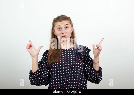 Mädchen in einem schwarzen Kleid überraschte schockierte Frau hebt Zeigefinger nach oben Stockfoto