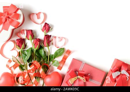 Geschenkbox und rote Rosen mit rotem Herzband isoliert auf weißem Hintergrund, Hintergrundkonzept Valentinstag Stockfoto