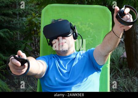 Der Mann, der das Virtual Reality Headset verwendet, genießt ein Spiel und erlebt die computergenerierte Simulation Stockfoto