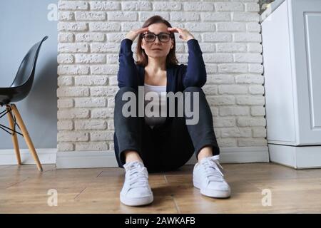 Traurige depressive Alter einsame Frau auf dem Boden sitzend. Stockfoto