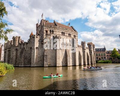 Gent, Belgien, ca. August 2019. Menschen mit Kajak und einem Kreuzfahrtschiff neben dem Schloss der Zählungen neben dem Fluss Lys. Schöne Architektur und l. Stockfoto