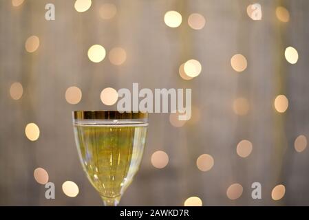 Glas Champagner, die festlichen Lichter einer Girlande verschwimmen im Hintergrund, das Konzept eines Urlaubs und Festes mit Sekt Stockfoto