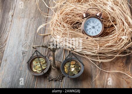 Zeit und Geld Ausgleichen ist Geldkonzept mit Münzhaufen mit Sanduhr auf Holztisch. Stockfoto