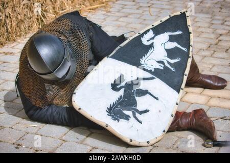 Ein Mittelalterritter in voller Körperbewaffnung, der verletzt auf dem Boden liegt Stockfoto