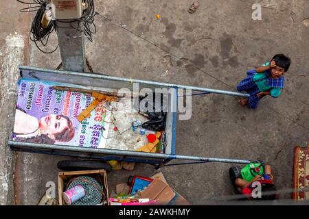 Ein obdachloses und verwirrtes junges asiatisches Schnitzelmädchen, das in Armut lebt, blickt in der Nähe eines Müllwagens auf einem Bürgersteig in Kampong Cham, Kambodscha, auf. Stockfoto