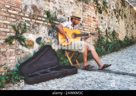 Granada/Spanien - 21. August 2019: Ein männlicher Busker sitzt in Gasse auf der spanischen Akustikgitarre Stockfoto