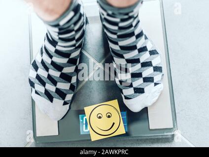 Nahaufnahme der Person in Socken auf der Badezimmer-Skala mit lächelndem Gesicht, ideales Körper-Wight-Konzept Stockfoto