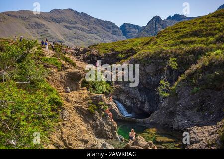 Glenspröde, Schottland/Großbritannien - 27. Juni 2019: Urlauber schwimmen in den Fairy Pools, die kalte Schwimmbäder, mehrere Wasserfälle sind, die lebhaft blau sind Stockfoto