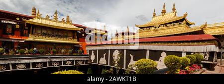 Panoramablick auf das Dach des Jokhang-Tempels. Das antike Gebäude ist ein UNESCO-Weltkulturerbe. Tibetischer Buddhismus. Dach mit goldenfarbenem Dharma-Rad. Stockfoto