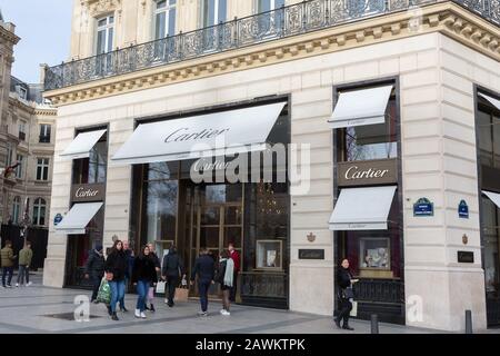 Seitenansicht auf dem Cartier-Laden an den Champs-Elysées. Menschen (Käufer?) mit Taschen laufen vorbei. Die Marke "Cartier" gehört zur Richemont Group. Stockfoto
