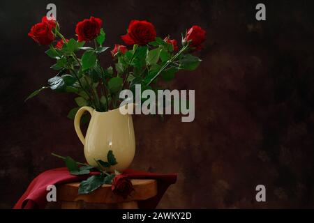 Ein stimmungsvoller Foto von roten Rosen in einer gelben Vase. Stockfoto