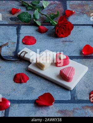 Herzförmige Marzipanbonbons und eine Rose zum valentinstag Stockfoto