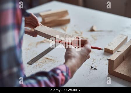 Tischlerhands messen mit Bleistift aus Holzpfanne. Konzept der Heimwerkerarbeit und Möbelherstellung Stockfoto