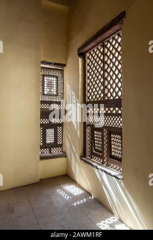 Ecke zweier verzierter Fenster aus Interleaved Grunge aus Holz - Mashrabiya - in Steinmauer am verlassenen Gebäude Stockfoto