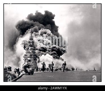 Das Flugdeck der USS Bunker Hill (CV-17) von Okinawa EWW2, wobei ihre Besatzung Brände durch zwei japanische Kamikaze-Treffer bekämpft. Ensign Kiyoshi Ogawa und sein Flügelspieler, die mit 550-Pfund-Bomben bewaffnete Kämpfer der Typen Mitsubishi A6M Zero-Sen (Allied Code Name 'Zeke') flogen, schlugen am 11. Mai 1945 um 1005 Stunden auf den Bunker Hill ein. Unterstützt von niedrigen Wolken und der aus General Quarters gesicherten Flotte überraschten die Selbstmordpiloten die Amerikaner und stürzten in Flugzeuge, die voll betankt und bewaffnet zum Start waren. Durch die Explosionen kam es zu Benzinfeuern auf dem Flugdeck und im Hangar. Okinawa Pazifischer Ozean - Zweiter Weltkrieg Stockfoto