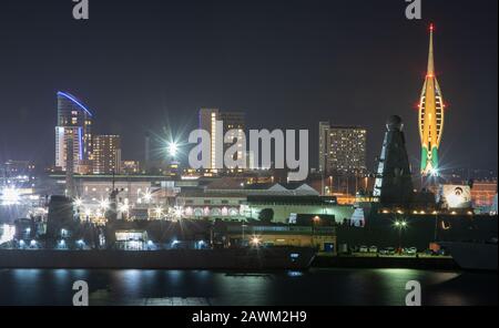 HMNB Portsmouth Her Majesty's Dockyard Portsmouth nachts mit Schiffen der Royal Navy und Gunwharf im Hintergrund mit dem Emirates Spinnaker Tower Stockfoto