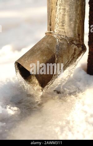 Drainpipe an der Ecke des Hauses mit Eis bedeckt Stockfoto