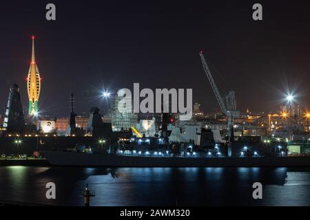 HMNB Portsmouth Her Majesty's Dockyard Portsmouth nachts mit Schiffen der Royal Navy und Gunwharf im Hintergrund mit dem Emirates Spinnaker Tower Stockfoto