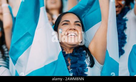 Frau mit Girlande und Argentinien-Fahnen jubeln aus Stadion-Fanzone. Argentinische Fußballfans jubeln aus dem Stadion. Stockfoto