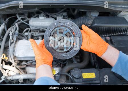 Automechaniker Tragen von Handschuhen hält alte Kupplungsscheibe über ein Auto Motor Stockfoto