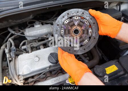 Automechaniker Tragen von Handschuhen hält alte Kupplungsscheibe über ein Auto Motor Stockfoto