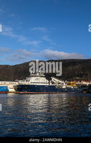 Offshore AHTS Anker Handling Schlepper liefern Leichtbauschiff Island Valiant, berthed im Hafen von Bergen, Norwegen. Ein dunkler, regnerischer und nebeliger Winde Stockfoto