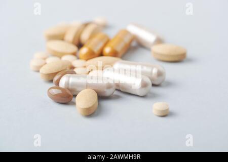 Mehrfarbige Vitamine und Ergänzungen auf hellem Papierhintergrund. Konzept für eine gesunde Nahrungsergänzungskost. Stockfoto