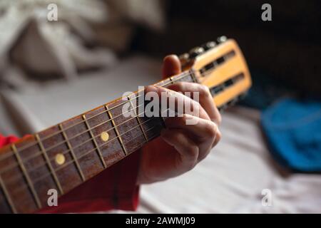 Guy spielt eine Melodie auf einer Akustikgitarre, während er seine Hand auf dem Fretboard hält. Stockfoto