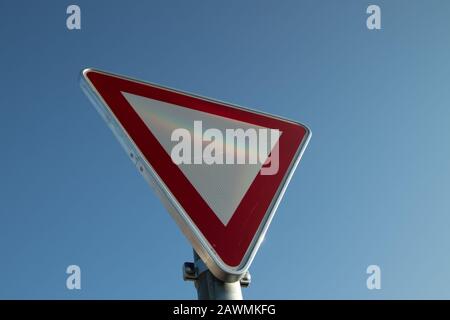 Deutsches Straßenschild Give Way, perspektivische Sicht, blauer Himmel Stockfoto