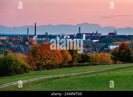 Panoramabild der Skyline von Augsburg bei Sonnenuntergang mit Bergen im Hintergrund. Stockfoto