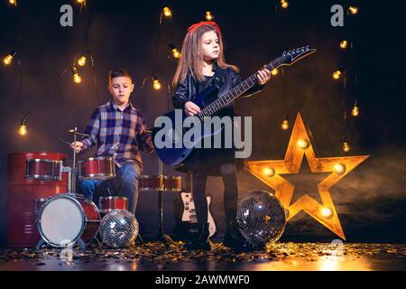 Kinder geben vor, in einer Rockband zu sein und im Studio oder auf der Bühne zu spielen und zu singen. Stockfoto