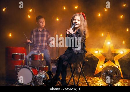 Kinder geben vor, in einer Rockband zu sein und im Studio oder auf der Bühne zu spielen und zu singen. Stockfoto