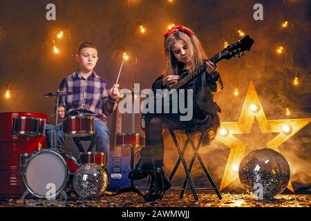 Kinder geben vor, in einer Rockband zu sein und im Studio oder auf der Bühne zu spielen und zu singen. Stockfoto