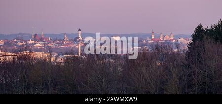 Panoramabild der Skyline von Augsburg bei Sonnenuntergang mit Bergen im Hintergrund. Stockfoto