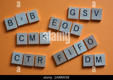 Akronyme für Unternehmen, darunter B2B, Business to Business und EOD, Ende des Tages, in 3D-Buchstaben aus Holzalphabet auf orangefarbenem Hintergrund Stockfoto