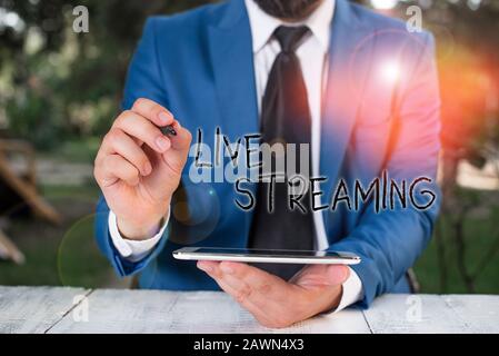 Konzeptionelles Handschreiben mit Live Streaming. Konzept bedeutet, dass Medien gleichzeitig aufgezeichnet und in Echtzeit Übertragen Werden, Wenn Ein Geschäftsmann mit Stift zeigt Stockfoto