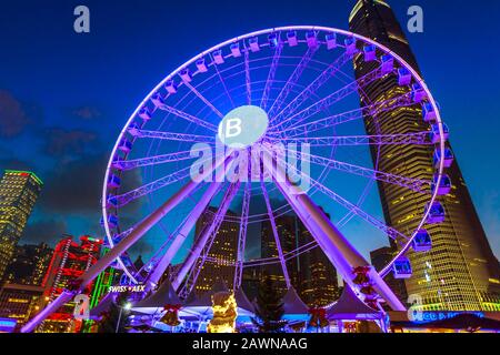 Hongkong, China - 11. Dezember 2016: Das Beobachtungsrad der Insel Hongkong nachts in der Nähe des Ferry Pier mit Wahrzeichen und Banks HQs in Stockfoto