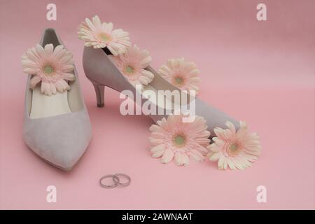 Hochzeitkonzept: Gerbera Blumen, Ringe, beige Schuhe auf pinkfarbenem Hintergrund. Kopierbereich Stockfoto