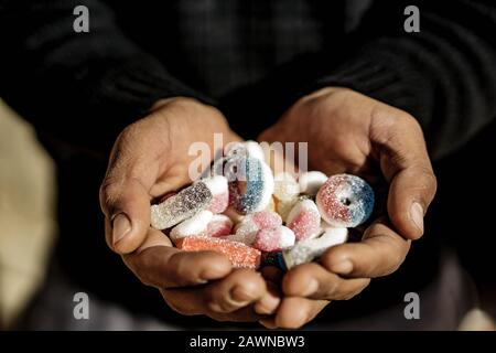 Person, die Jelly Beans auf einem verschwommenen Hintergrund hält Stockfoto