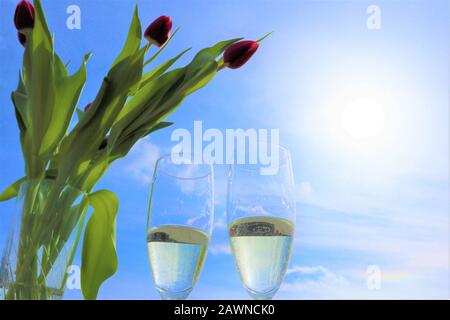 Zwei Weingläser mit Spumante, Prosecco, Champagner, rote Tulpen auf blauem Himmel Hintergrund, sonniger Tag. Kopierbereich Stockfoto