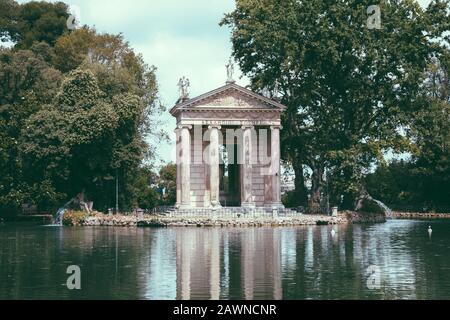 Panoramablick auf den Tempel des Asklepios (Tempio di Esculapio) und See in den öffentlichen Park der Villa Borghese. Tag Sommer und blauer Himmel Stockfoto