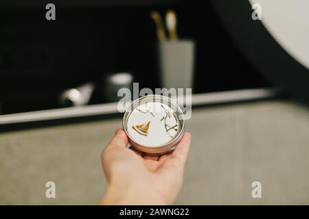 Handfestes Shampoo aus Metall in der Hand in modernem Badezimmer auf dem Hintergrund eines eleganten schwarzen Regals mit kostenlosen natürlichen, natürlichen Biobaumteilen aus Kunststoff. Null Stockfoto