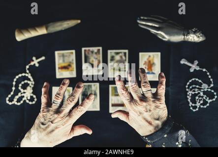 Alte Frau hält ihre Hände über Tarot-Karten. Alte faltige Hände. Okkultes Wahrsagerkonzept. Bild von oben aufgenommen. Stockfoto