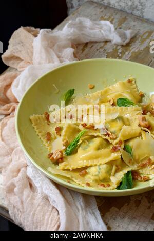 Italienische Küche. Hausgemachte frische Ravioli-Pasta mit Spinat und Ricotta-Käse, frischem Basilikum und schwarzem Pfeffer, Parmesankäse und Buttersauce auf LIGH Stockfoto