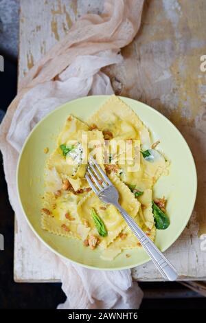 Italienische Küche. Hausgemachte frische Ravioli-Pasta mit Spinat und Ricotta-Käse, frischem Basilikum und schwarzem Pfeffer, Parmesankäse und Buttersauce auf LIGH Stockfoto