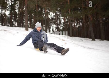 Erwachsener reitet von einem steilen Berg aus auf Schlitteneis. Winterspaß. Stockfoto